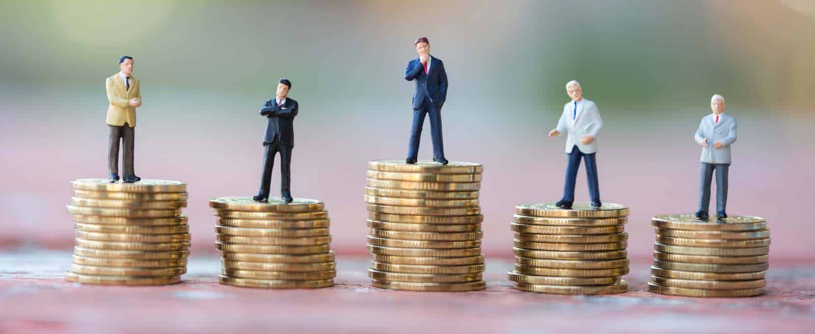 Cinco figuras de negocios sobre montones de monedas de distinta altura